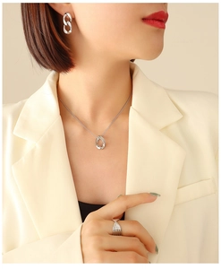 Set di gioielli in argento con collana, orecchini e anello indossati da modella in tailleur