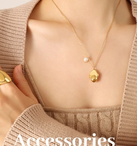 Close-up of gold titanium necklace featuring a white pearl and irregular geometric pendant