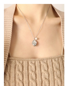 Detailed close-up of a silver geometric fluid metal pendant with white pearl on a fine chain