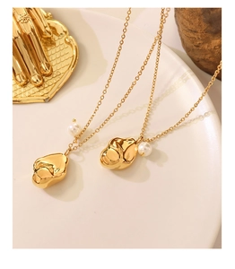 Detailed macro view of 18K gold plated necklace with irregular lava pendant and pearl accent