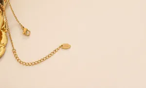 Detailed macro view of 18K gold-plated stainless steel necklace clasp and engraved tag