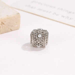 Macro view of silver hollow floral bead with white pearl accents for DIY jewelry