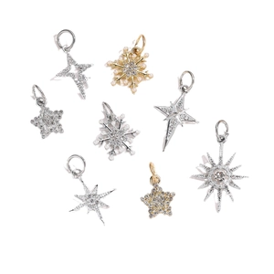 Macro shot of zircon-studded star and snowflake pendants with pearls in gold and silver