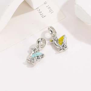 Macro detail of silver dragon charms with light blue and yellow enamel wings for DIY jewelry