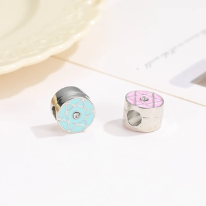Macro shot of silver hexagram beads with light blue and soft pink enamel and zircon center