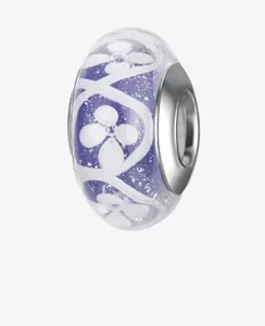 Detailed macro view of purple glass charm bead with white flower pattern and silver core