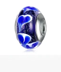 Macro detail of blue glass charm bead with white heart pattern and silver core