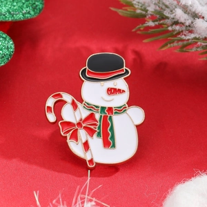 Close-up of a snowman enamel brooch with a top hat and candy cane on red festive background