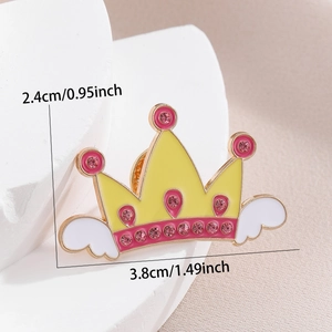 Detail view of a yellow crown enamel pin with wings and pink rhinestones, 3.8cm wide