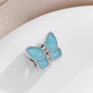 Macro view of a delicate silver butterfly charm with blue enamel and zircon stones