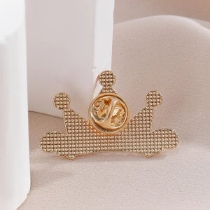 Macro view of golden crown brooch back showing textured metal and butterfly clutch pin