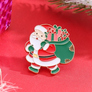 Close-up of enamel Santa Claus brooch with red hat and green gift bag on red fabric