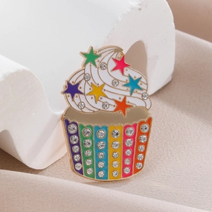 Macro detail of cupcake brooch with colorful stars and rainbow rhinestones in gold setting