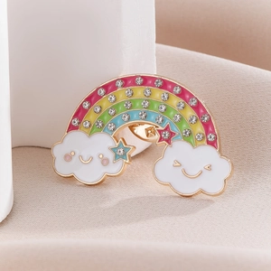 Detailed view of a rainbow enamel brooch with sparkling rhinestones and smiling clouds