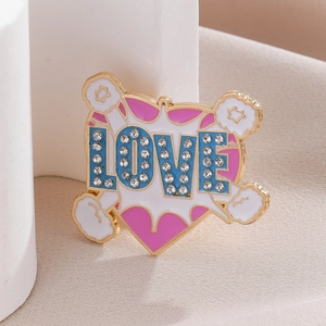 Detail of pink heart LOVE brooch with sparkling rhinestones and white enamel clouds