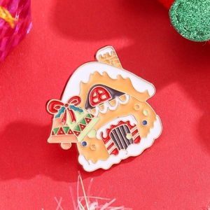Macro shot of gingerbread house enamel brooch with Christmas bells on a festive red surface