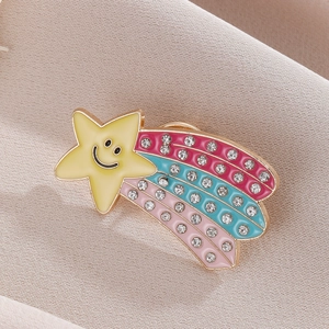 Macro shot of colorful enamel rainbow star brooch with rhinestones on beige fabric