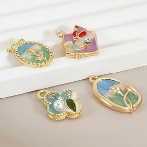 Detail von floralen Emaille-Anhängern mit Vergoldung und Perlenakzenten für DIY-Schmuck