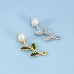 Macro shot of gold and silver leaf charms with green enamel and white pearls