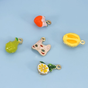 Macro detail of five enamel fruit charms including lemon and strawberry with gold plating