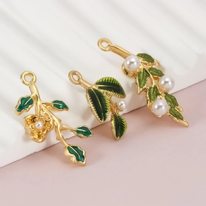 Detail of gold pendants with green enamel leaves and white pearls for DIY jewelry