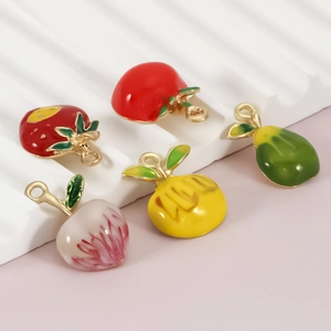 Macro detail of colorful enamel fruit charms including strawberry and peach for DIY jewelry