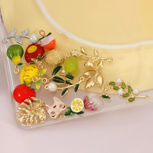 Close-up of colorful enamel fruit pendants like lemon and pear for DIY jewelry making