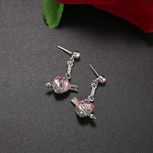 Minimalist silver heart earrings with iridescent crystal and rose floral background