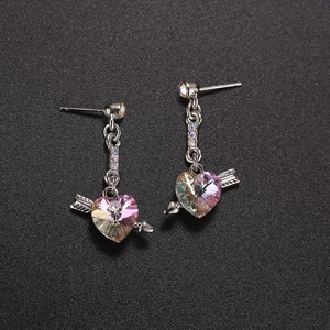 Detail view of Cupid's arrow heart earrings with faceted rainbow crystals on black background