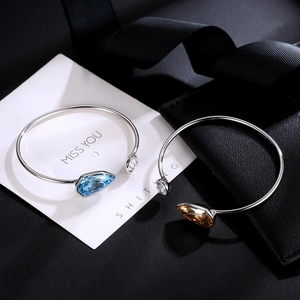 Elegant silver bracelets with teardrop blue and amber crystals on a black base