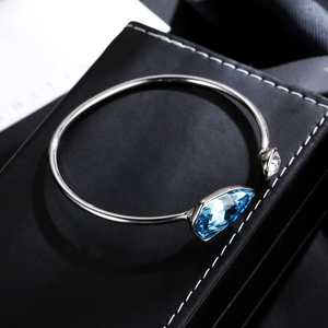 Detail of silver open bangle with dual blue geometric crystals on black leather case