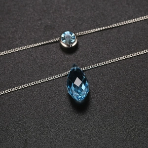 Detalle del colgante de cristal azul en gota de agua y gema redonda en cadena de plata