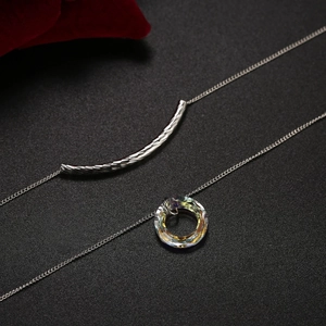 Detalle del collar con colgante de cristal y tubo metálico en una cadena de plata fina