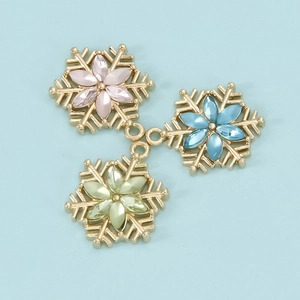 Three colorful snowflake pendants in pink, blue, and green with gold metal frames for DIY jewelry