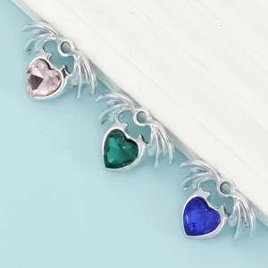Macro detail of heart-shaped winged pendants with pink, green and blue gemstones