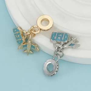 Close-up of travel themed airplane and blue enamel suitcase charms with zircon inlay