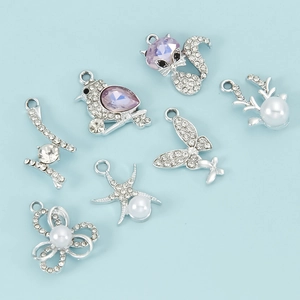 Detalle de colgantes plateados con pedrería púrpura y perlas para joyería artesanal