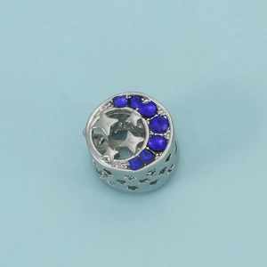 Macro detail of star and crescent moon charm bead with blue crystals in silver