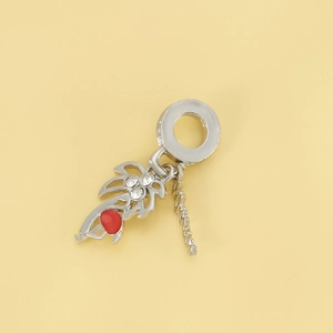 Silver coconut tree charm with white zircons and red enamel on a pale yellow background