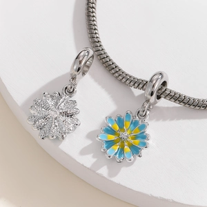 Detailed macro view of a silver snake chain bracelet with daisy floral pendants