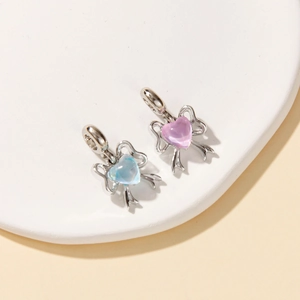 Close-up of heart-shaped ribbon bow charms in pink and blue with silver bases