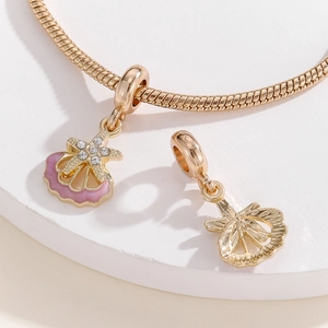 Detailed close-up of a gold snake chain bracelet with pink enamel shell and starfish charms