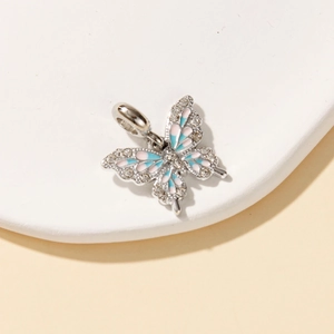 Detailed macro view of silver butterfly charm with pink and blue enamel and clear zircons