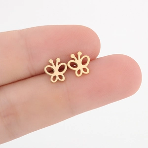 Goldene hohle Schmetterlings-Ohrstecker zwischen den Fingern für einen Größenvergleich