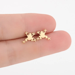 Nahaufnahme goldener Frosch-Ohrstecker aus poliertem Edelstahl an den Fingern