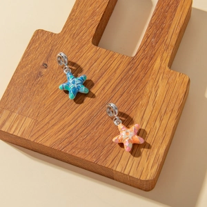 Macro detail of starfish enamel jewelry charms in colorful blue and warm orange tones