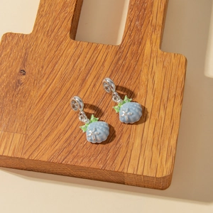 Detailed view of light blue enamel shell and starfish charms on a wooden display stand