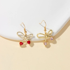 Close-up of bow earrings with red and pink heart-shaped gemstones on white stones