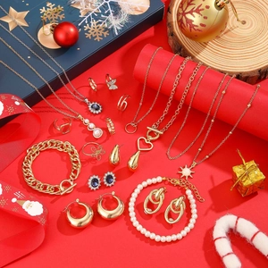 Flat lay of the full Christmas jewelry set with gold necklaces and earrings on red background