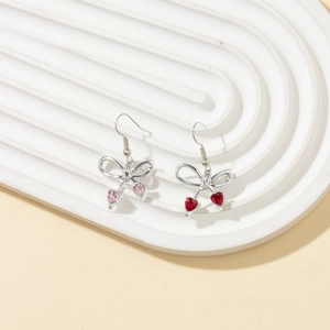 Detail of bow-shaped drop earrings with faceted pink and dark red heart crystals